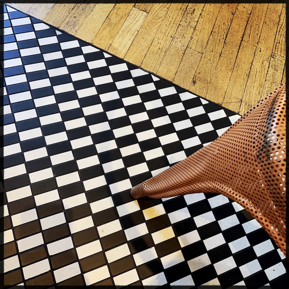 Carrelage en damier, parquet bois et pied de chaise métal